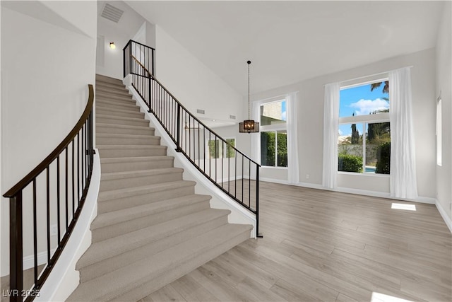 stairway featuring baseboards, visible vents, and wood finished floors