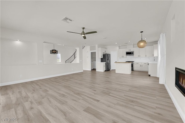 unfurnished living room featuring light wood-style floors, a ceiling fan, baseboards, recessed lighting, and visible vents