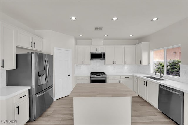 kitchen with stainless steel appliances, tasteful backsplash, a sink, and a center island