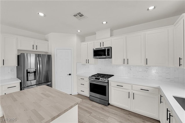 kitchen featuring appliances with stainless steel finishes, white cabinets, and visible vents