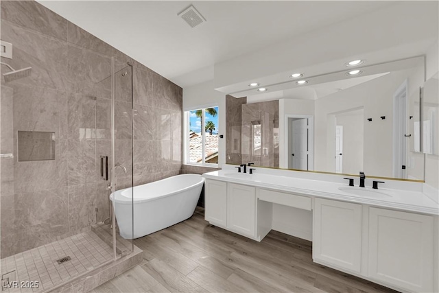 full bathroom with a sink, visible vents, a soaking tub, and a stall shower
