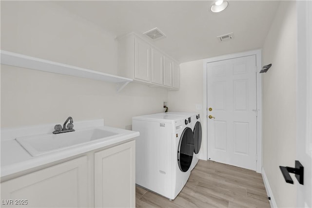 clothes washing area with visible vents, a sink, cabinet space, and washer and dryer
