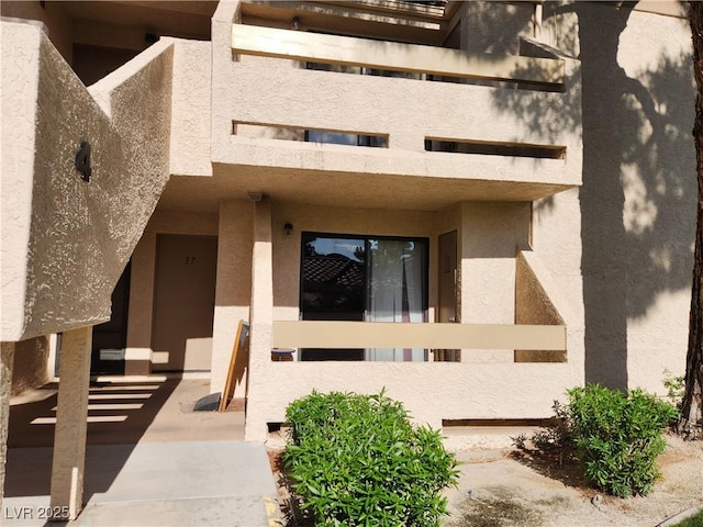 entrance to property with a balcony and stucco siding