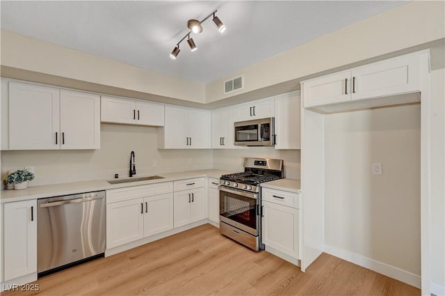kitchen featuring appliances with stainless steel finishes, a sink, and white cabinets