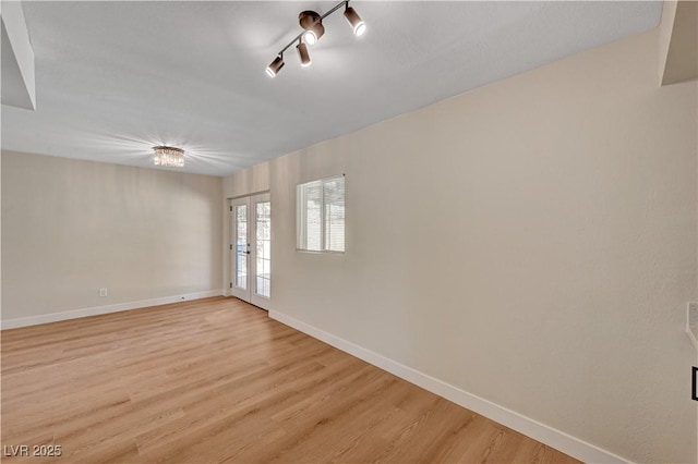 unfurnished room featuring light wood-type flooring, baseboards, and rail lighting