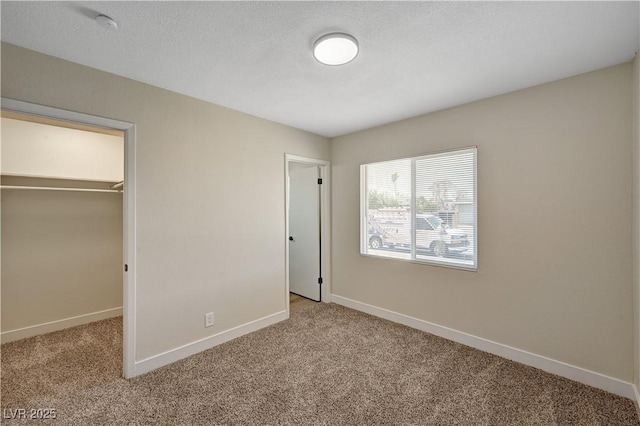 unfurnished bedroom featuring carpet floors, baseboards, a spacious closet, and a closet