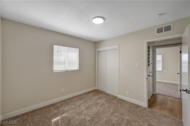 unfurnished bedroom featuring multiple windows, a closet, baseboards, and carpet floors