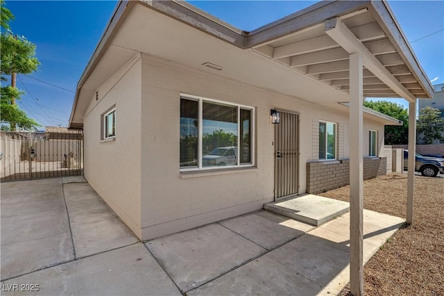 exterior space featuring a patio, fence, and concrete block siding