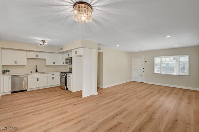 unfurnished living room featuring light wood-style flooring, recessed lighting, a chandelier, a sink, and baseboards