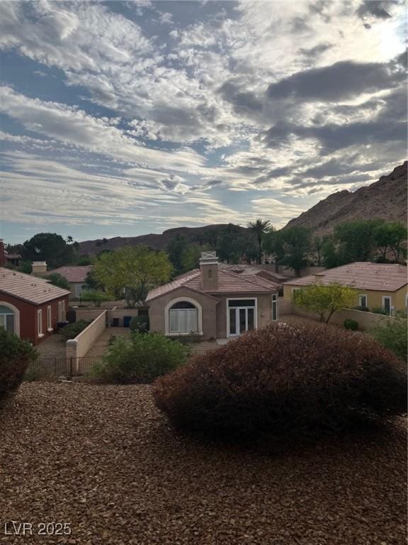 exterior space featuring fence, a mountain view, a chimney, and stucco siding