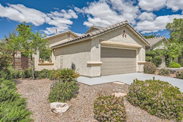 view of side of property with fence, an attached garage, stucco siding, concrete driveway, and a tiled roof
