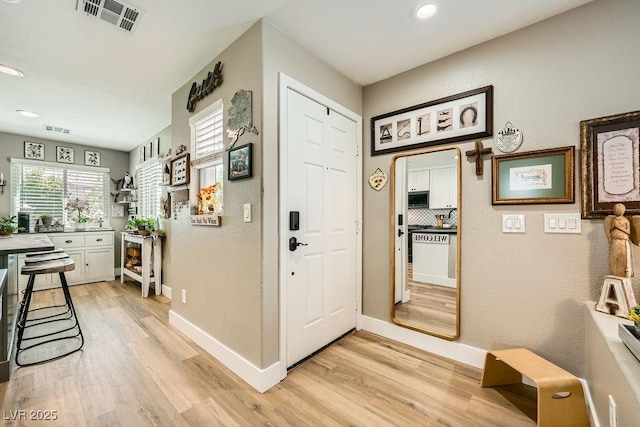 hallway featuring recessed lighting, baseboards, light wood finished floors, and visible vents