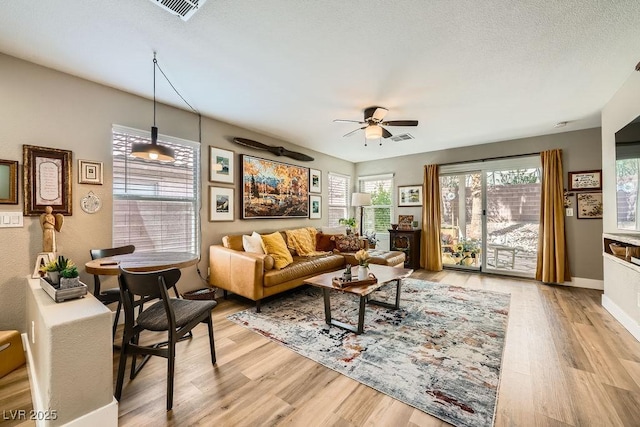 living area with light wood-style floors, a ceiling fan, and visible vents
