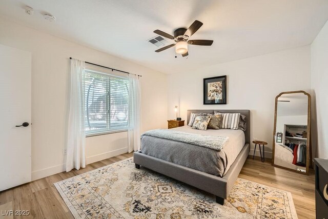 bedroom with light wood-style floors, baseboards, a ceiling fan, and visible vents