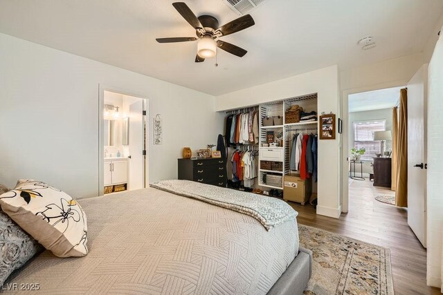 bedroom with ceiling fan, visible vents, wood finished floors, a closet, and ensuite bathroom