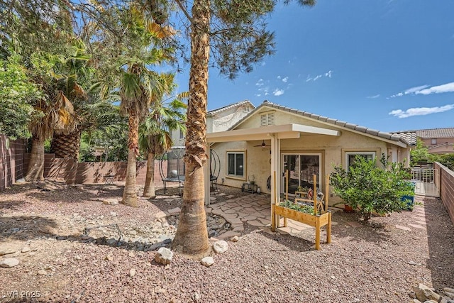 rear view of house featuring a tiled roof, ceiling fan, a fenced backyard, a patio, and stucco siding