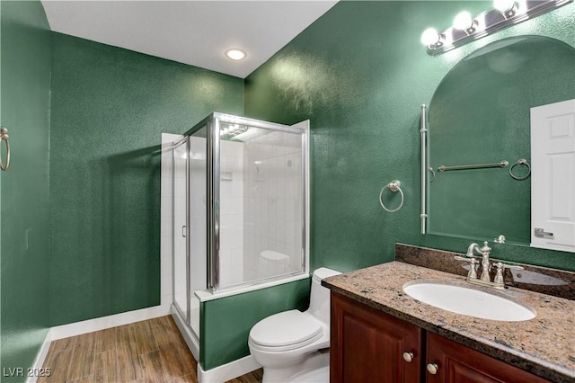 bathroom featuring a shower stall, wood finished floors, baseboards, toilet, and a textured wall