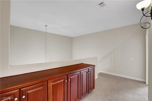 corridor featuring baseboards, light colored carpet, and visible vents