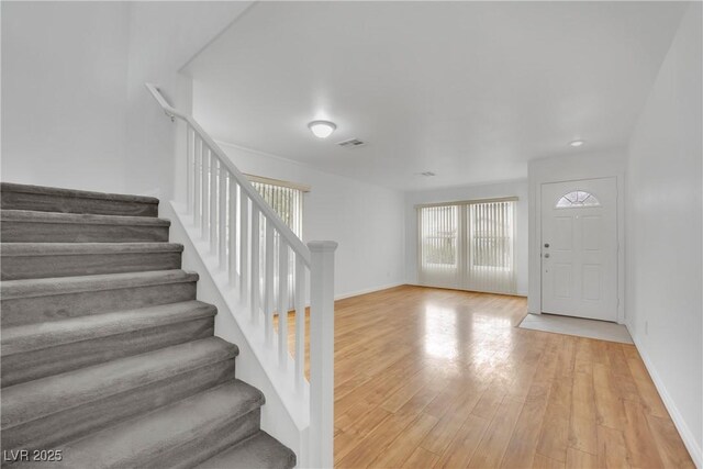 entrance foyer featuring stairway, baseboards, and light wood-style flooring