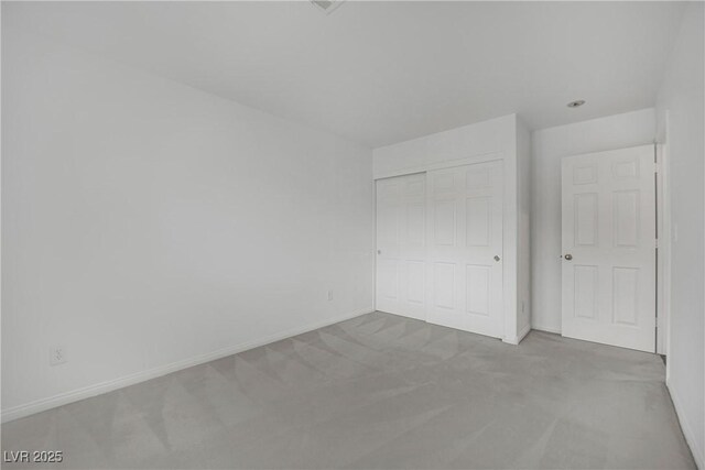 unfurnished bedroom featuring carpet floors, baseboards, and a closet