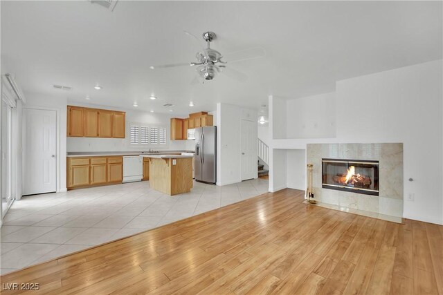kitchen with white dishwasher, stainless steel fridge with ice dispenser, light countertops, a center island, and open floor plan