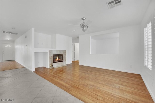 unfurnished living room with visible vents, a ceiling fan, baseboards, and light tile patterned floors