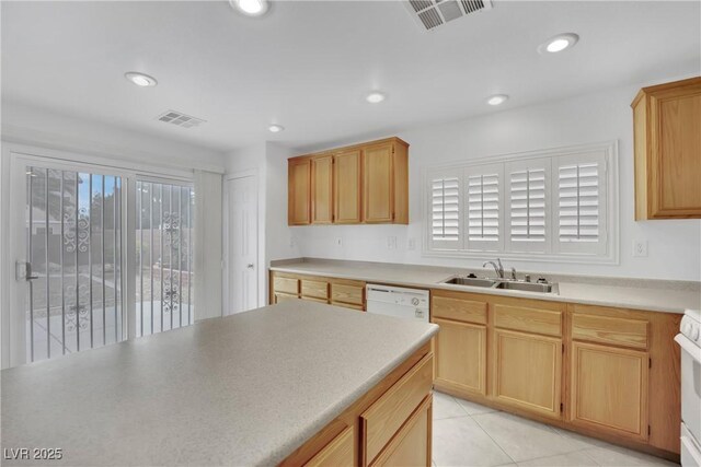 kitchen featuring a sink, light brown cabinetry, white appliances, and visible vents