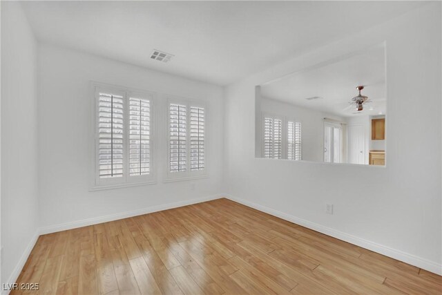 unfurnished room with baseboards, ceiling fan, wood finished floors, and visible vents