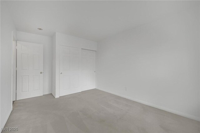 unfurnished bedroom with baseboards, carpet, and a closet