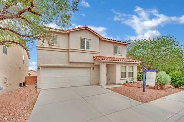 mediterranean / spanish house with a garage, a tiled roof, concrete driveway, and stucco siding