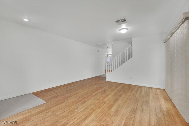 unfurnished living room featuring baseboards, light wood-type flooring, stairs, and visible vents