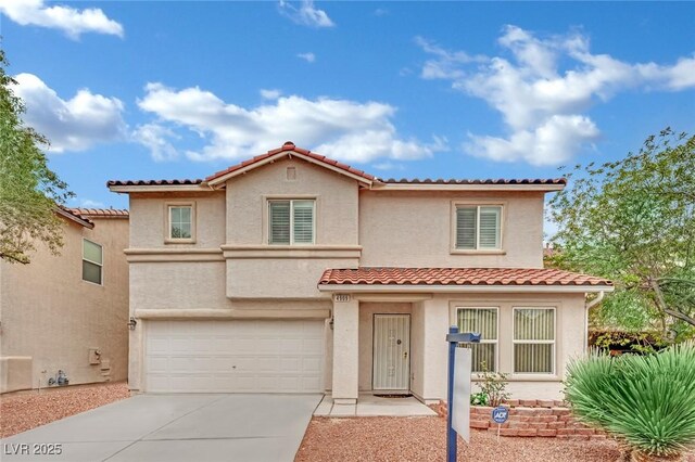 mediterranean / spanish home with a garage, stucco siding, a tiled roof, and concrete driveway