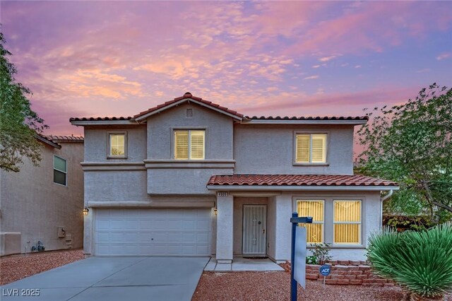 mediterranean / spanish-style home featuring a garage, stucco siding, concrete driveway, and a tile roof