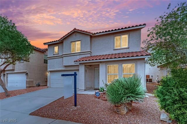 mediterranean / spanish home with a tiled roof, stucco siding, driveway, and a garage