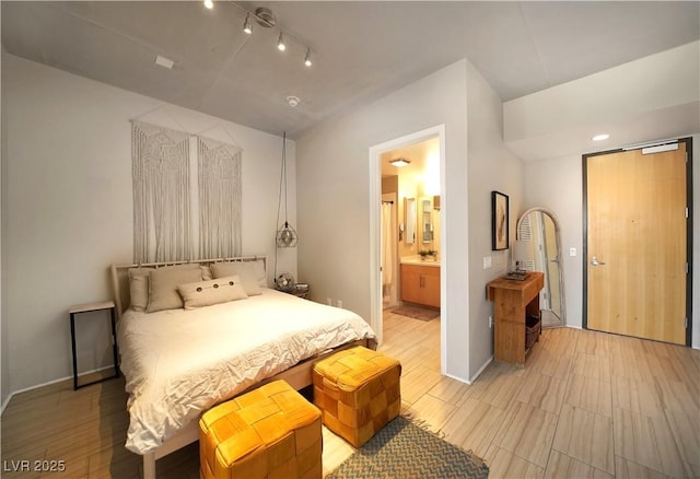 353 E Bonneville Ave Unit 215, Las Vegas, NV 89101 - bedroom with light wood finished floors, rail lighting, ensuite bath, and baseboards