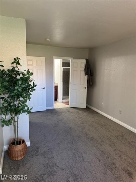 4965 Indian River Dr Unit 101, Las Vegas, NV 89103 - unfurnished bedroom featuring dark carpet, baseboards, and ensuite bath