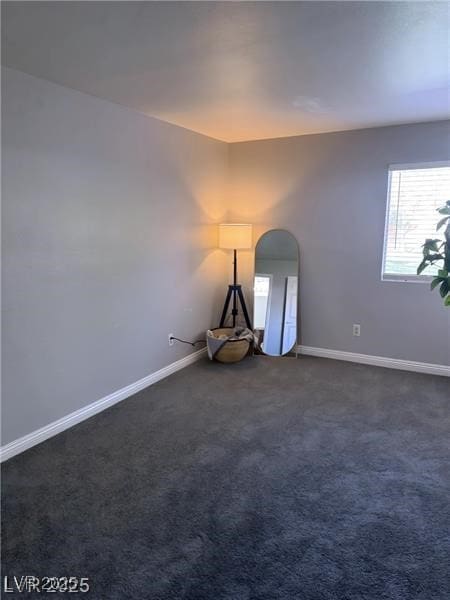 4965 Indian River Dr Unit 101, Las Vegas, NV 89103 - unfurnished room with arched walkways, baseboards, and dark carpet
