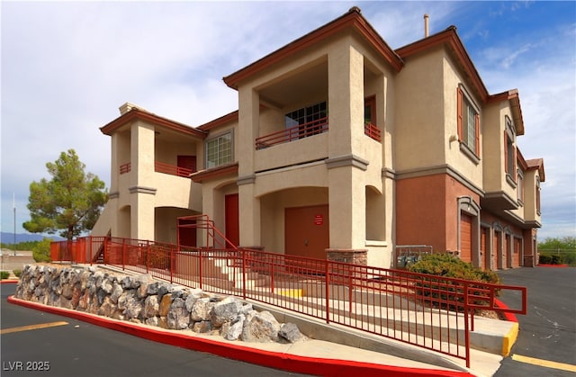1608 Sussex St Unit 204, Las Vegas, NV 89144 - view of front of property with an attached garage, stucco siding, a balcony, and fence