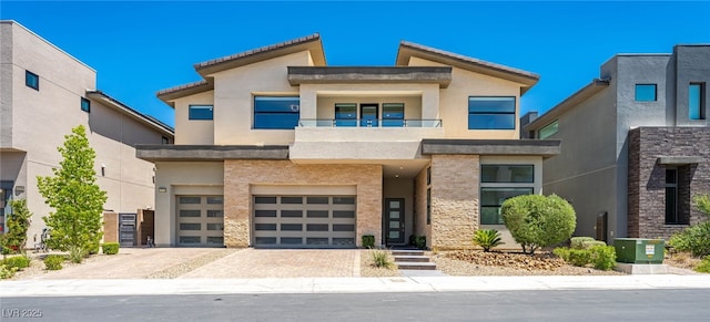 contemporary home with central air condition unit, decorative driveway, an attached garage, and stucco siding