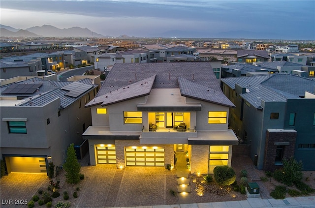 contemporary home featuring driveway, a residential view, a garage, a balcony, and stucco siding