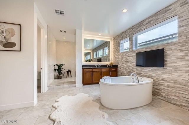full bath featuring a freestanding tub, plenty of natural light, vanity, and visible vents