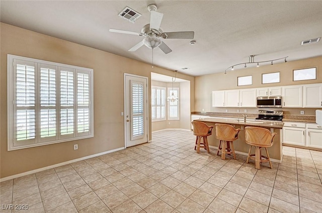 1574 Livingston Dr, Henderson, NV 89012 - kitchen with appliances with stainless steel finishes, light tile patterned flooring, a ceiling fan, white cabinets, and light countertops