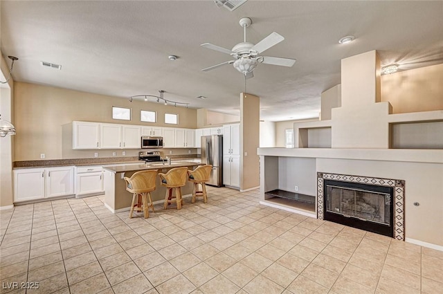 1574 Livingston Dr, Henderson, NV 89012 - kitchen with appliances with stainless steel finishes, light tile patterned flooring, a kitchen bar, and white cabinetry