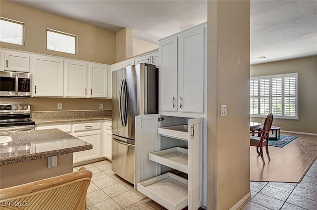 1574 Livingston Dr, Henderson, NV 89012 - kitchen featuring stainless steel appliances, light tile patterned floors, light stone countertops, and white cabinets