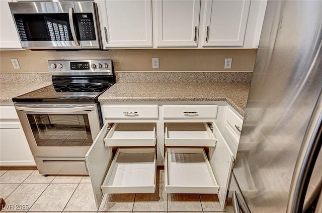 1574 Livingston Dr, Henderson, NV 89012 - kitchen with stainless steel appliances, white cabinetry, light tile patterned flooring, and light stone counters