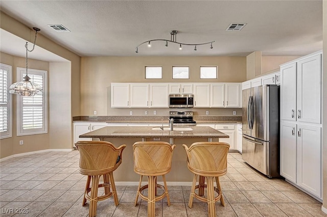 1574 Livingston Dr, Henderson, NV 89012 - kitchen with appliances with stainless steel finishes, a kitchen bar, white cabinetry, and an island with sink