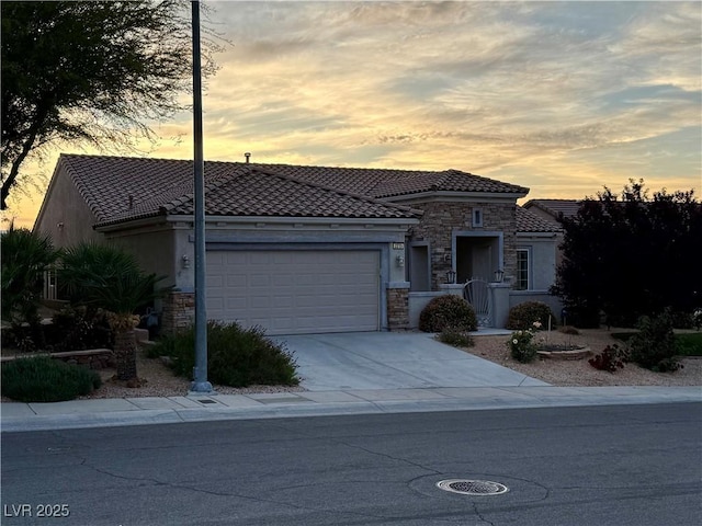 view of front facade with stone siding, a garage, stucco siding, a tiled roof, and driveway