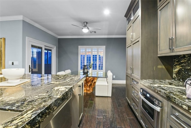kitchen with oven, dark stone countertops, baseboards, visible vents, and dark wood-style floors