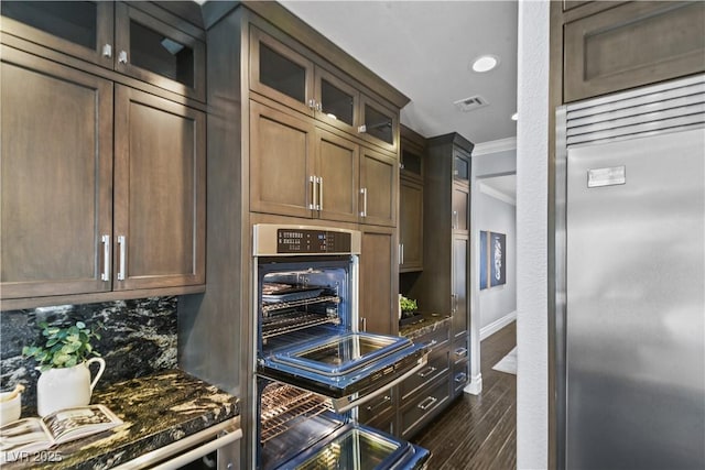 kitchen with decorative backsplash, visible vents, appliances with stainless steel finishes, ornamental molding, and dark wood-type flooring