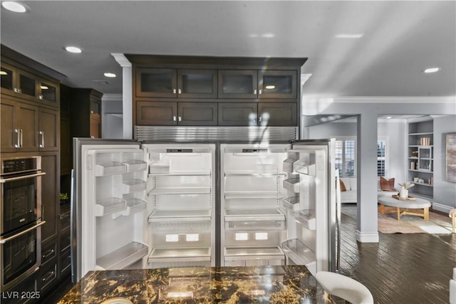 interior details featuring crown molding, double oven, recessed lighting, wood finished floors, and glass insert cabinets